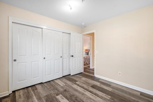 unfurnished bedroom with a closet and dark wood-type flooring