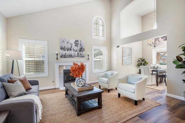 living room with a towering ceiling, a chandelier, and hardwood / wood-style floors