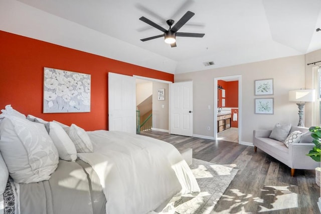 bedroom featuring vaulted ceiling, ceiling fan, dark hardwood / wood-style flooring, and connected bathroom