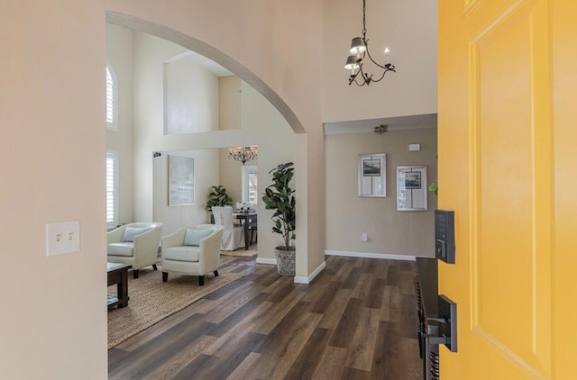 entryway featuring a high ceiling, dark wood-type flooring, a notable chandelier, and plenty of natural light