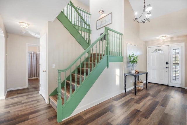 entrance foyer featuring a towering ceiling, dark hardwood / wood-style flooring, and an inviting chandelier