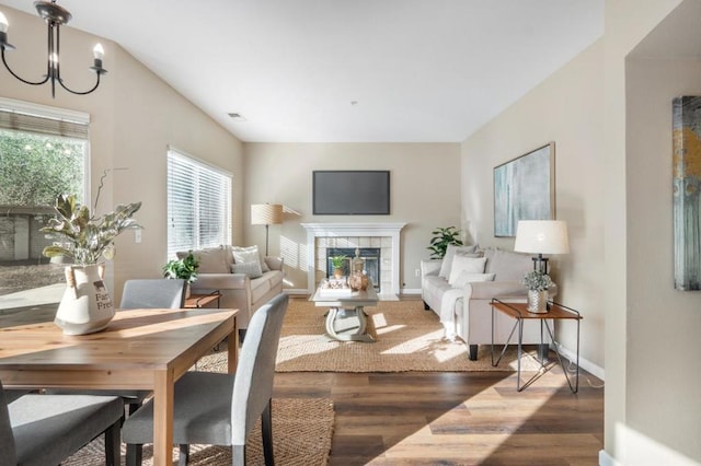 living room featuring a tile fireplace, a notable chandelier, and dark wood-type flooring