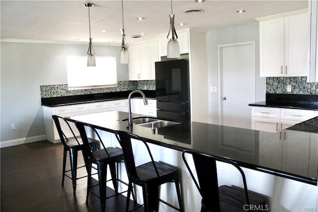 kitchen featuring tasteful backsplash, dark countertops, white cabinets, a sink, and black refrigerator