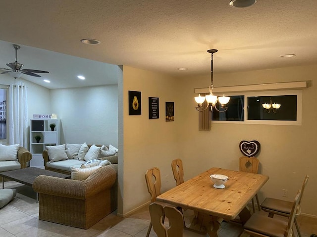 tiled dining room featuring a textured ceiling and ceiling fan with notable chandelier