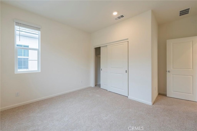 unfurnished bedroom featuring light carpet and a closet