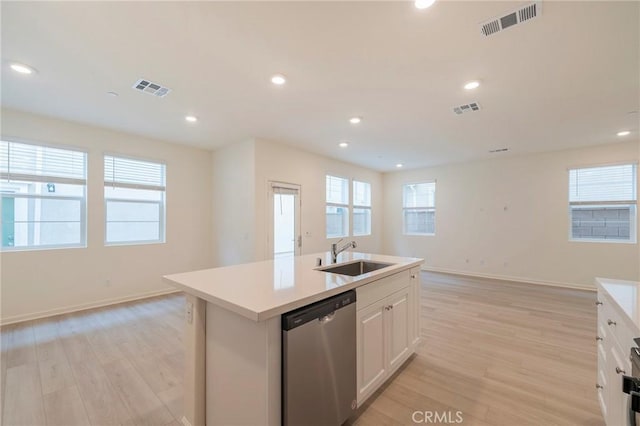 kitchen with light hardwood / wood-style floors, stainless steel dishwasher, sink, an island with sink, and white cabinets