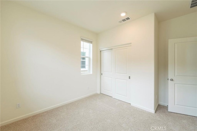 unfurnished bedroom featuring a closet and light carpet