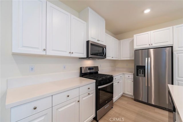 kitchen featuring white cabinets, stainless steel appliances, and light wood-type flooring