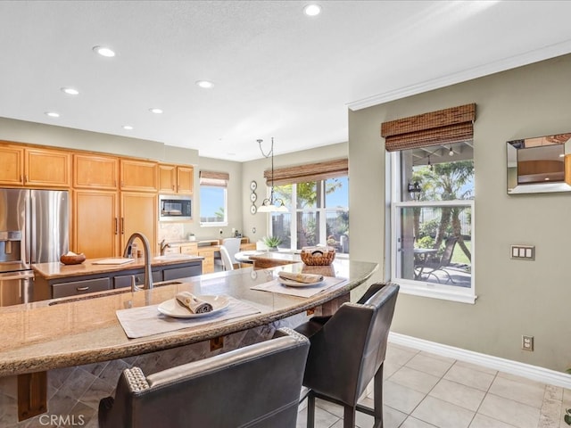 kitchen with a center island, light tile patterned floors, light stone countertops, built in microwave, and stainless steel fridge