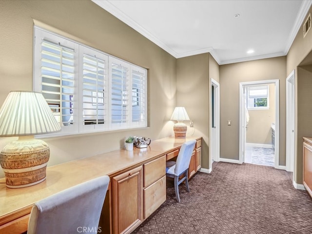 office space with crown molding, built in desk, dark colored carpet, visible vents, and baseboards