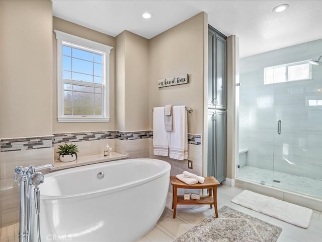 full bathroom featuring recessed lighting, tile walls, a soaking tub, a shower stall, and tile patterned floors