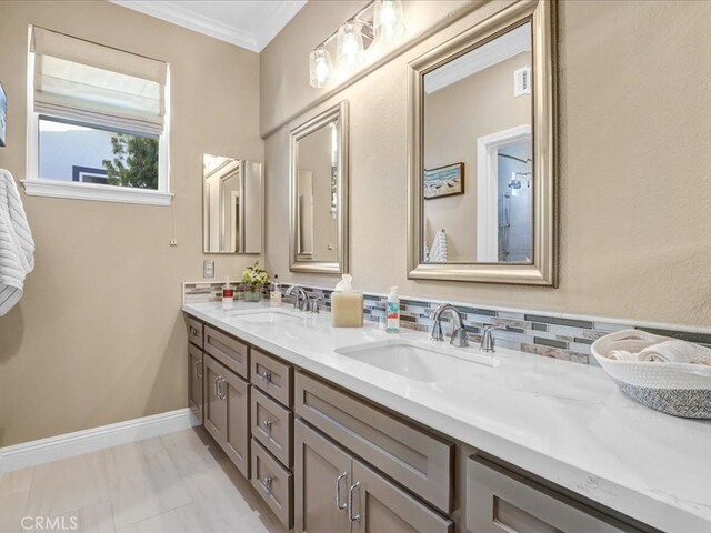 bathroom with double vanity, visible vents, ornamental molding, and a sink