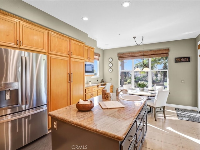 kitchen with light stone counters, a center island, stainless steel fridge, and light tile patterned floors