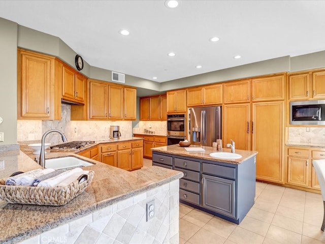 kitchen featuring visible vents, appliances with stainless steel finishes, a sink, and a center island