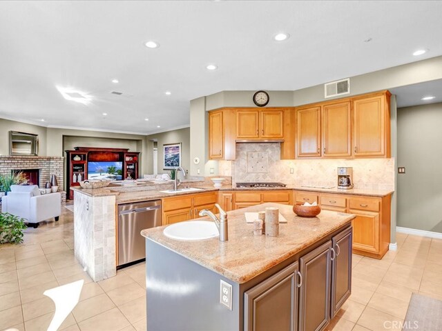 kitchen featuring light tile patterned floors, decorative backsplash, light stone countertops, stainless steel appliances, and a sink