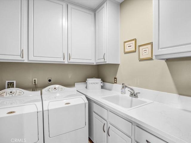 clothes washing area with cabinet space, a sink, and separate washer and dryer