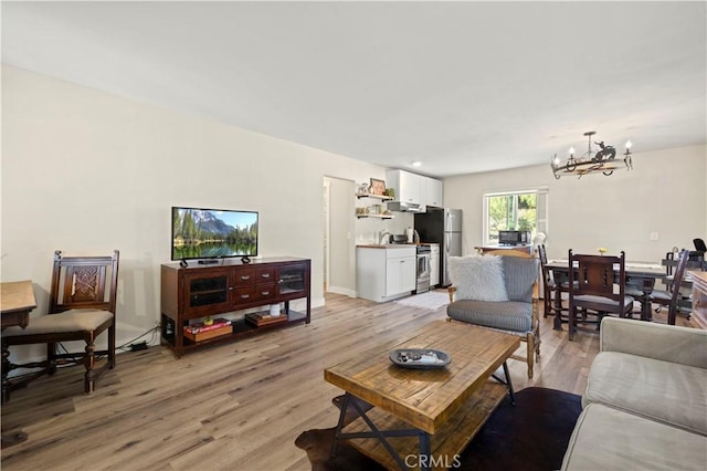 living room with light hardwood / wood-style floors and a notable chandelier