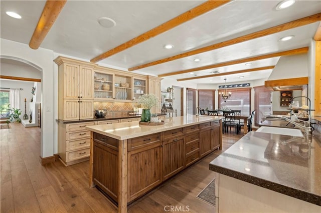 kitchen featuring dark hardwood / wood-style flooring, sink, an inviting chandelier, a large island, and dark stone counters