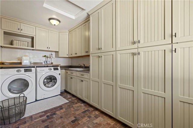 clothes washing area with washer and clothes dryer, sink, and cabinets