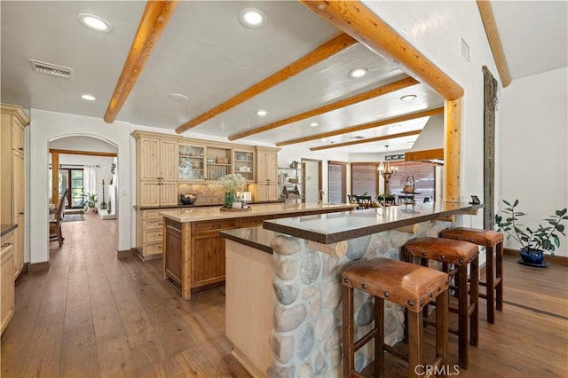 bar featuring decorative backsplash, wood-type flooring, beamed ceiling, and an inviting chandelier