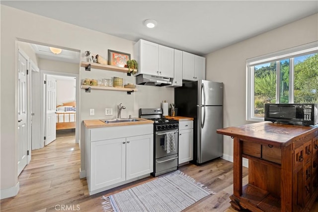 kitchen with sink, white cabinetry, appliances with stainless steel finishes, and light wood-type flooring