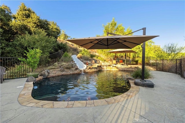 view of pool featuring a water slide, pool water feature, and a patio