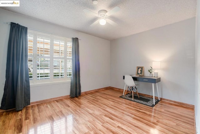 home office featuring a textured ceiling, ceiling fan, light hardwood / wood-style floors, and a healthy amount of sunlight