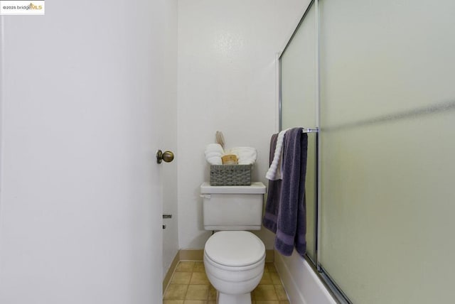 bathroom with combined bath / shower with glass door, tile patterned flooring, and toilet