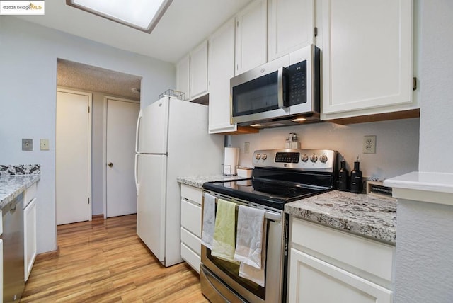 kitchen with light stone counters, stainless steel appliances, light wood-type flooring, and white cabinetry