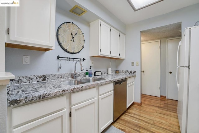 kitchen with light stone counters, dishwasher, white cabinets, white refrigerator, and sink