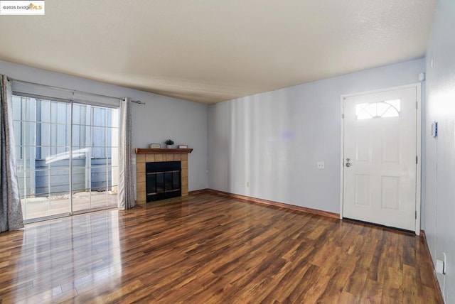 unfurnished living room featuring dark wood-type flooring and a tile fireplace