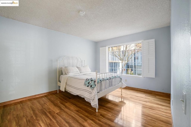 bedroom with a textured ceiling and hardwood / wood-style floors