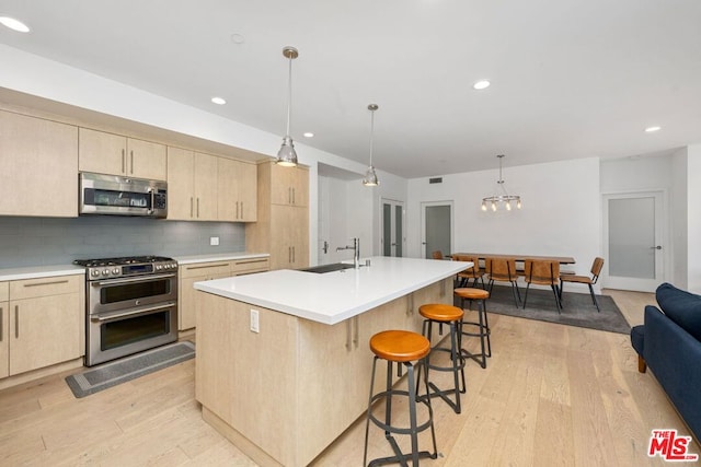 kitchen featuring stainless steel appliances, light brown cabinetry, sink, decorative backsplash, and a kitchen island with sink