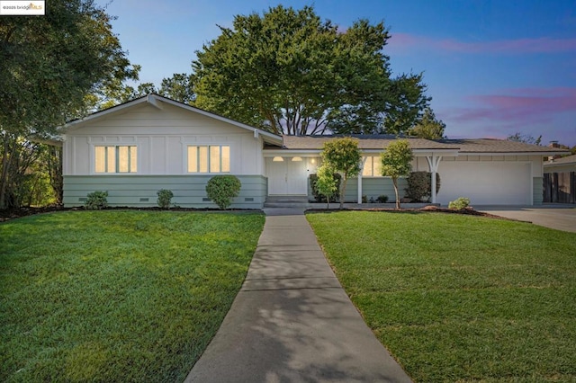 ranch-style house featuring a garage and a yard