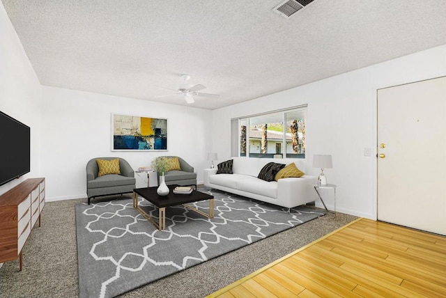 living room featuring a textured ceiling, ceiling fan, and hardwood / wood-style flooring