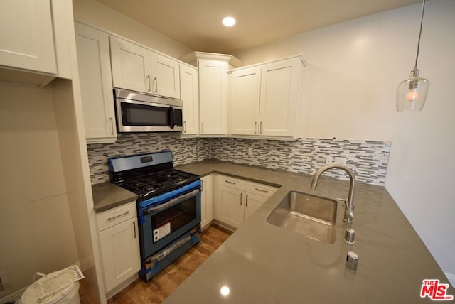 kitchen with white cabinetry, gas stove, hanging light fixtures, and sink