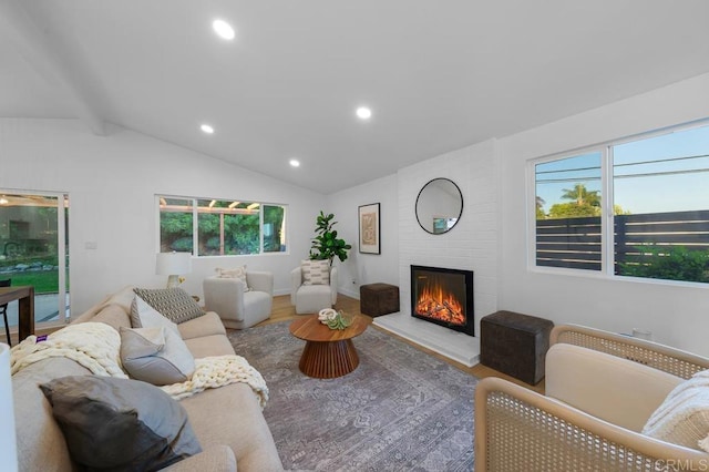 living room with hardwood / wood-style flooring, vaulted ceiling, and a large fireplace