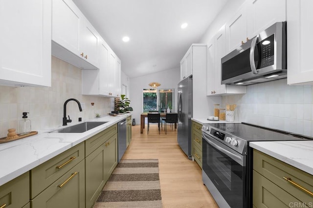 kitchen with lofted ceiling, sink, stainless steel appliances, light hardwood / wood-style floors, and green cabinetry