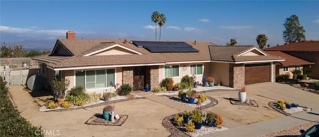 single story home featuring solar panels and a garage