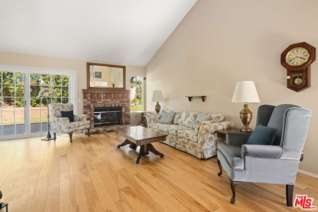 living room featuring vaulted ceiling, a fireplace, and light hardwood / wood-style flooring