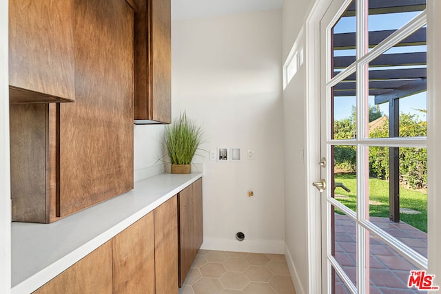 laundry area featuring light tile patterned floors, washer hookup, and cabinets