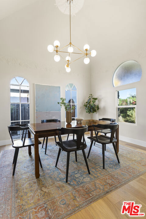 dining room with a towering ceiling, a chandelier, and hardwood / wood-style flooring