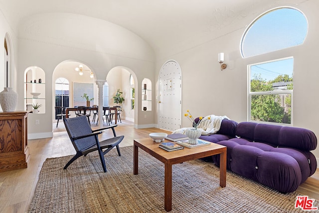 living room featuring plenty of natural light, light wood-type flooring, and vaulted ceiling