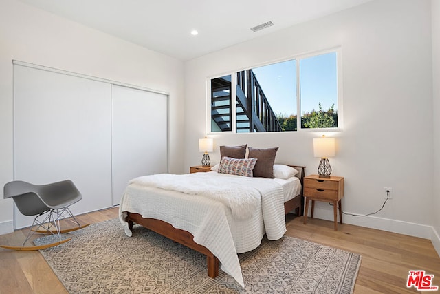 bedroom with light hardwood / wood-style flooring and a closet