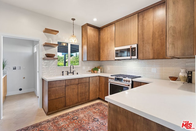 kitchen featuring kitchen peninsula, appliances with stainless steel finishes, backsplash, hanging light fixtures, and sink