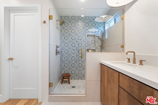 bathroom featuring hardwood / wood-style flooring, tiled shower, and vanity