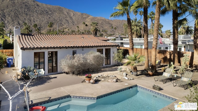 back of property featuring a patio area, a mountain view, and a fenced in pool