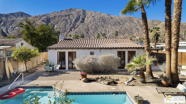 rear view of house featuring a fenced in pool, a mountain view, and a patio