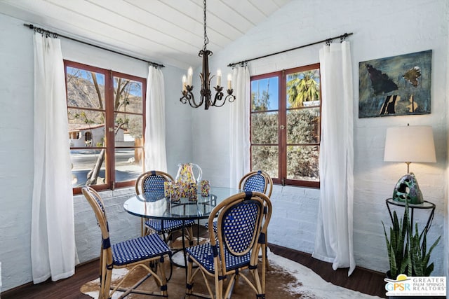 dining space with dark wood-type flooring, lofted ceiling, and a notable chandelier