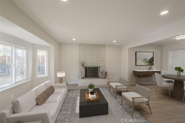 living room featuring light wood-type flooring and a brick fireplace